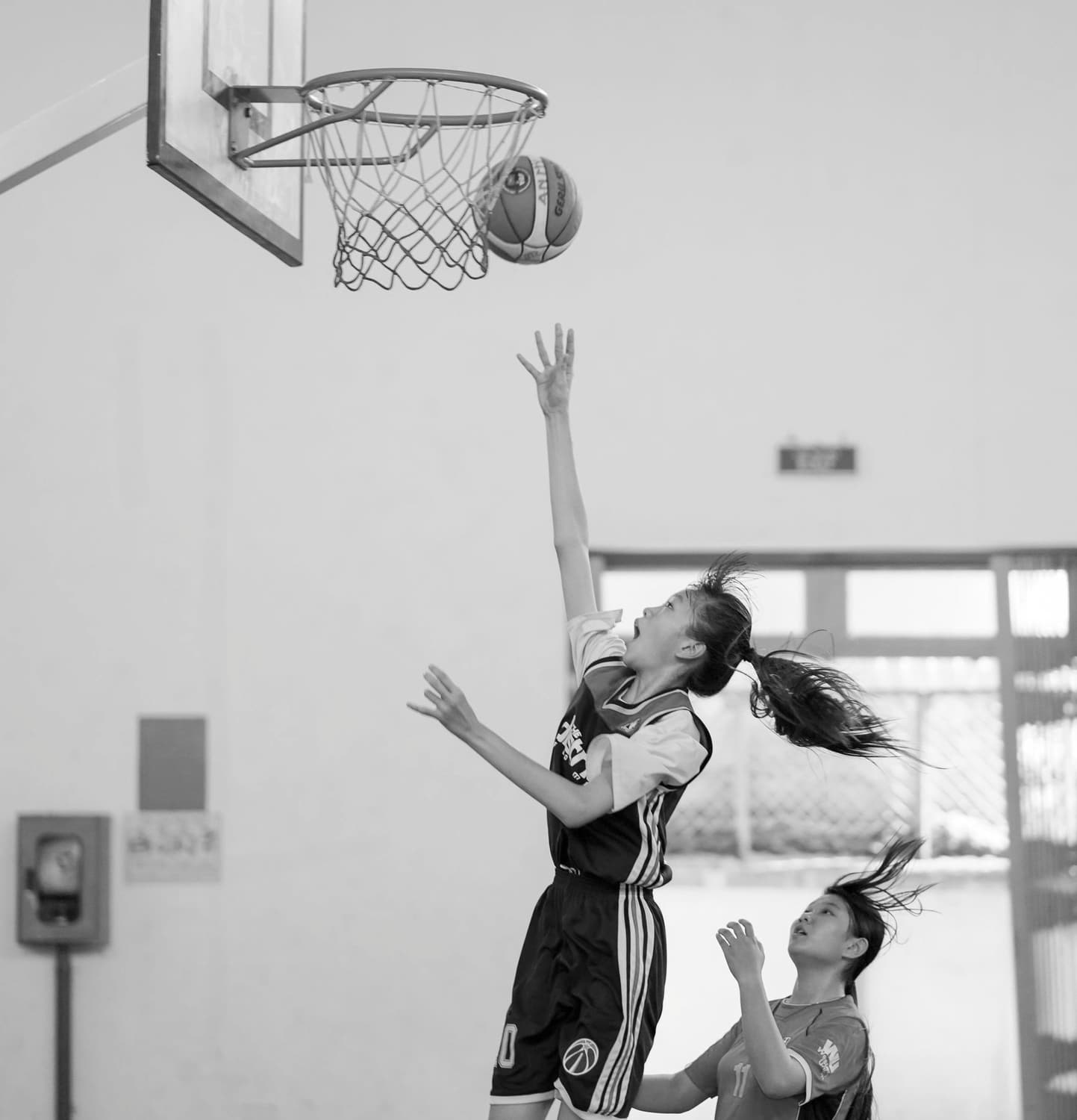 A basketball player rising for a layup under the hoop in a sports hall.